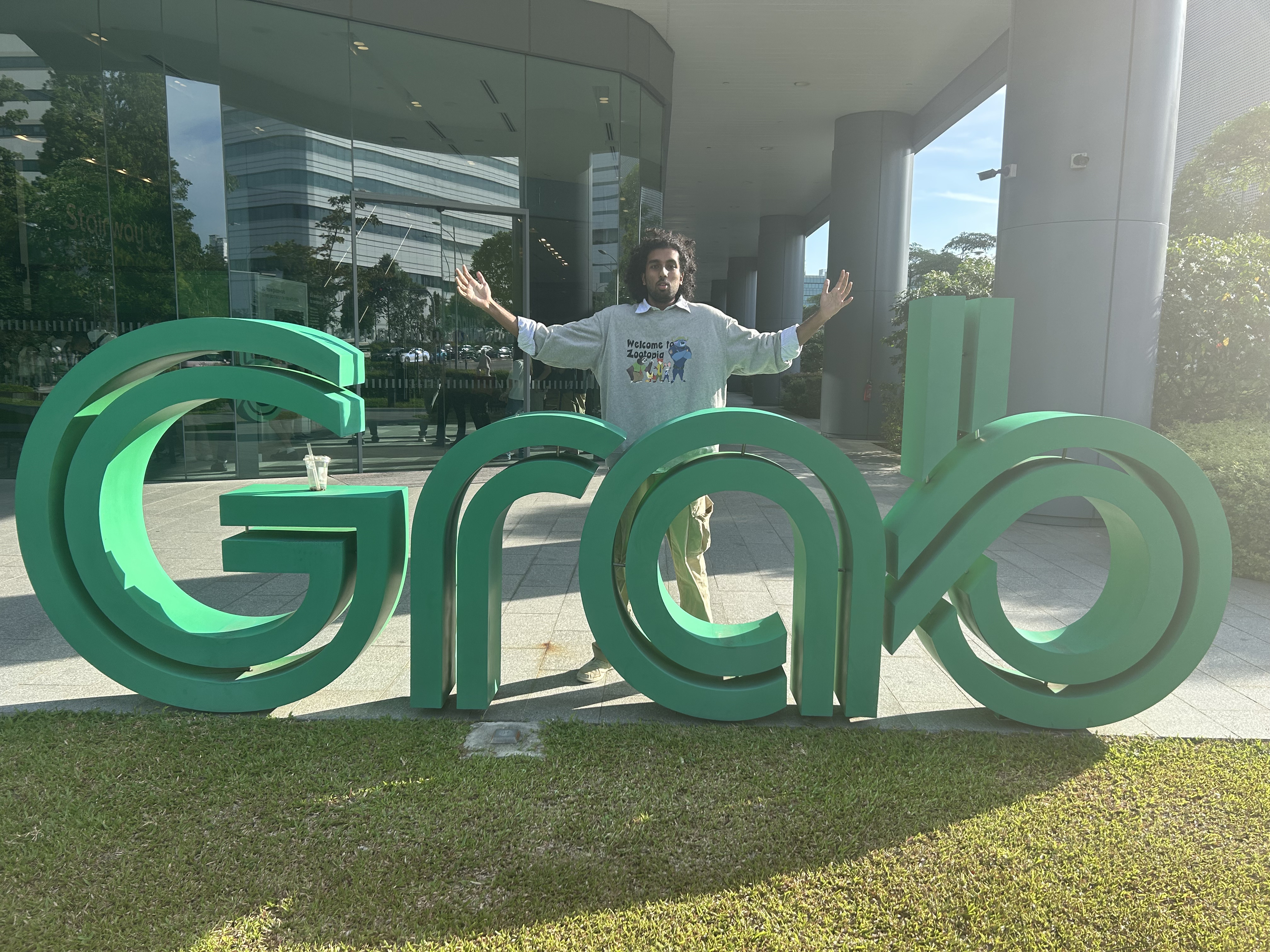 Gullapalli Chetan standing behind a Grab sign with arms open.